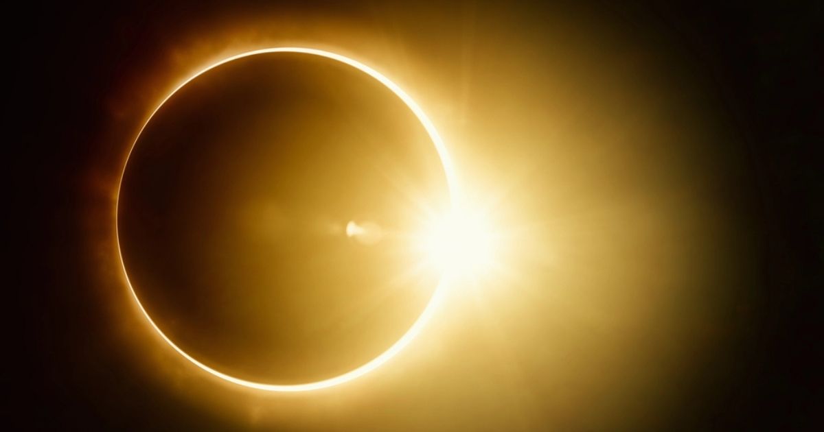 Ringvormige zonsverduistering waarbij de maan de zon bijna volledig bedekt, met een gouden lichtring zichtbaar aan de rand