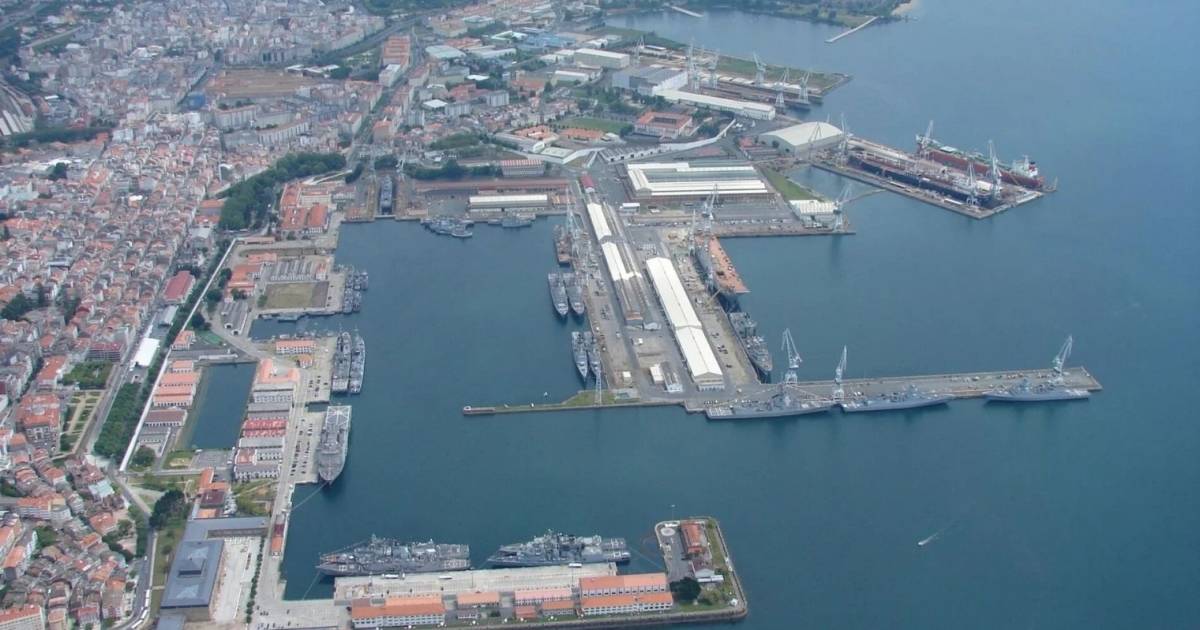 Luchtfoto van een marinehaven met meerdere oorlogsschepen aangemeerd aan kades, omgeven door stedelijke bebouwing