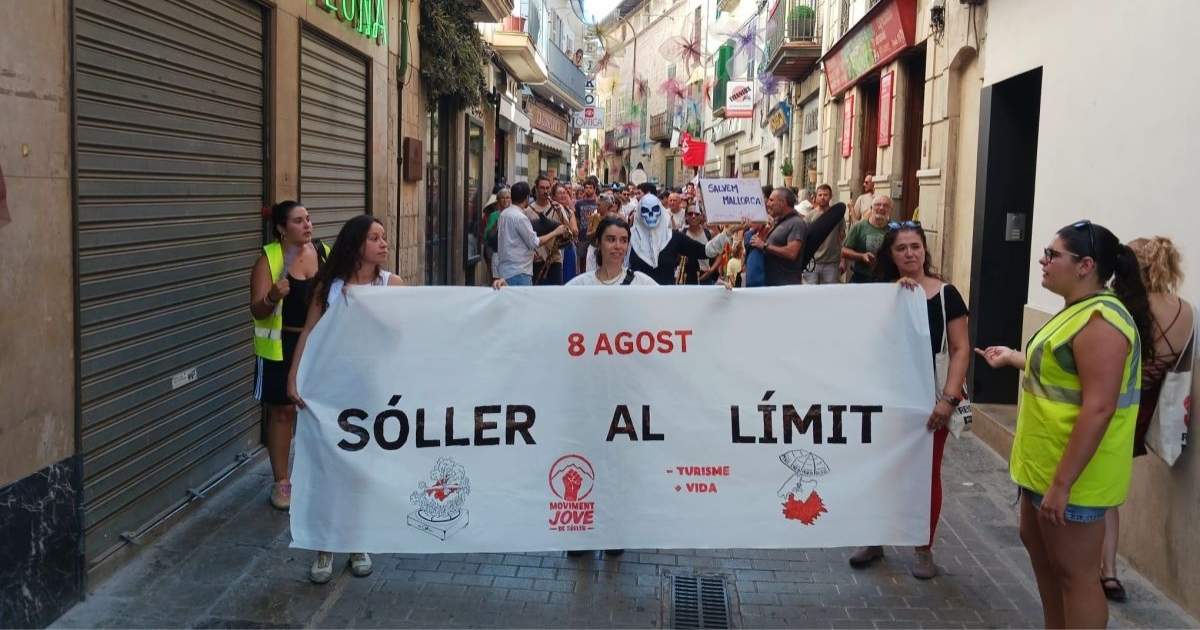 Demonstranten in Sóller dragen een spandoek met de tekst "8 Agost – Sóller al Límit – Menys Turisme, Més Vida