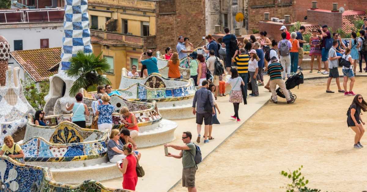 Drukke menigte toeristen bij het golvende mozaïekterras van Park Güell in Barcelona